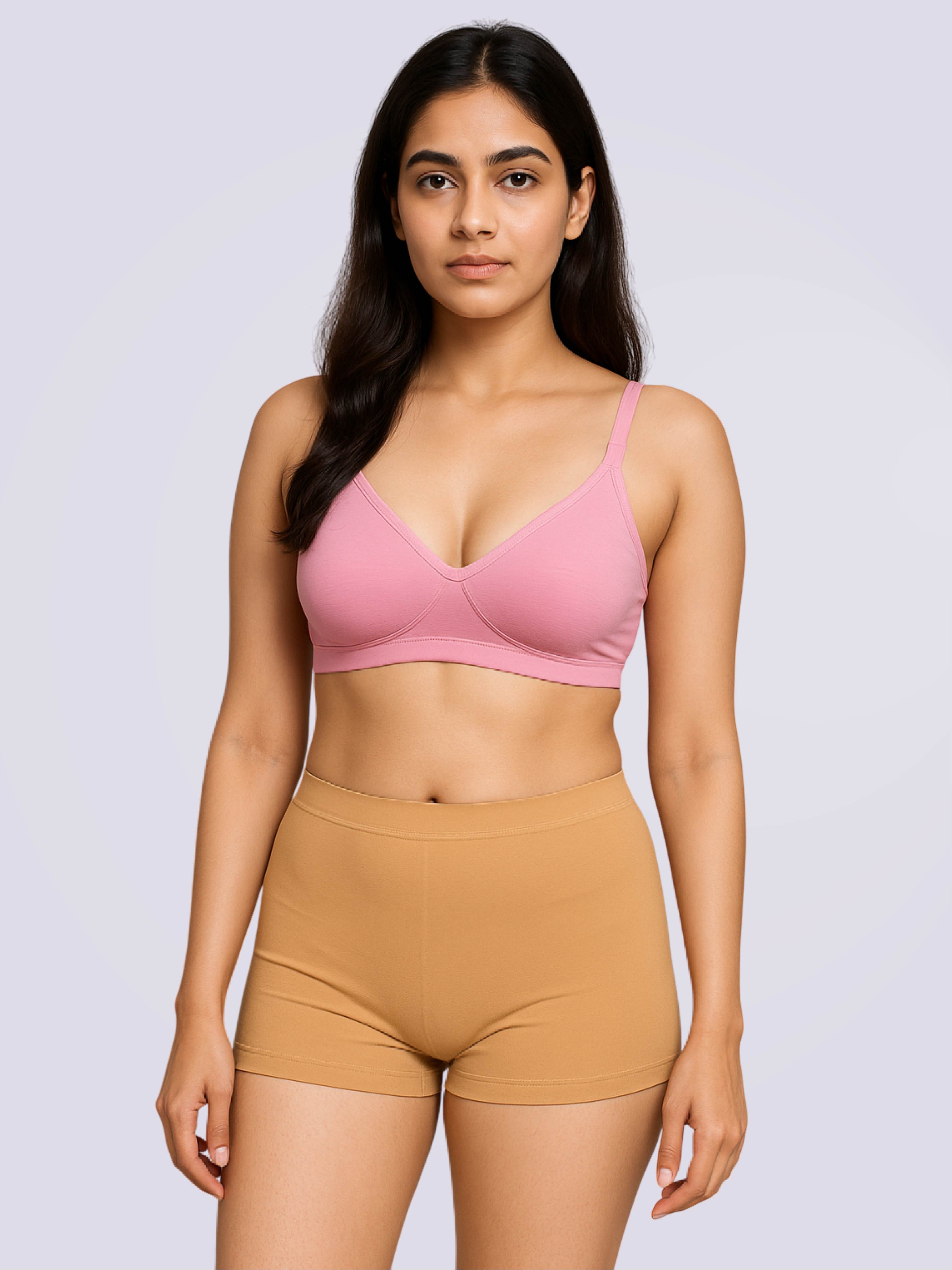 Woman wearing a pink bra and beige shorts on a light gray background